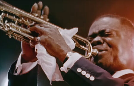 Louis Armstrong 1947 - A man in a blue suit playing a trumpet
