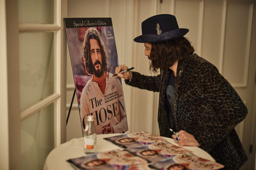 Jonathan Roumie signs the poster of 'The Chosen' Special Collector's Edition Issue of TV Guide Magazine