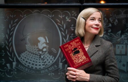 Lucy Worsley holding a copy of The Hound of the Baskervilles in front of The Sherlock Holmes Pub in London__