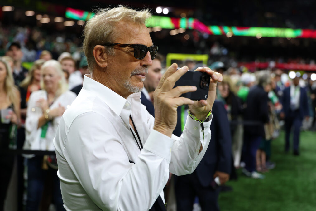 Kevin Costner takes photos on the field prior to Super Bowl LIX